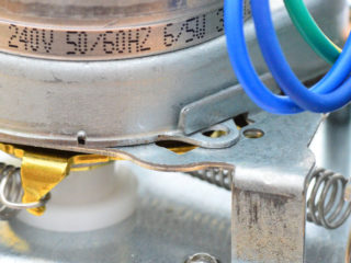 Metal retaining tab holding flange of Honeywell valve Synchron motor